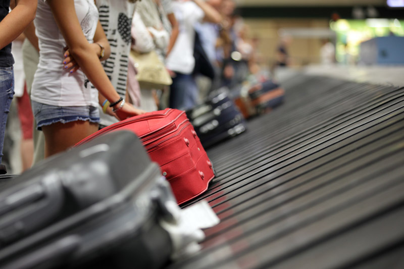 Person picking up luggage at an airport.